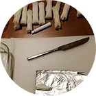 A palette knife and foil packet used in pigment making.